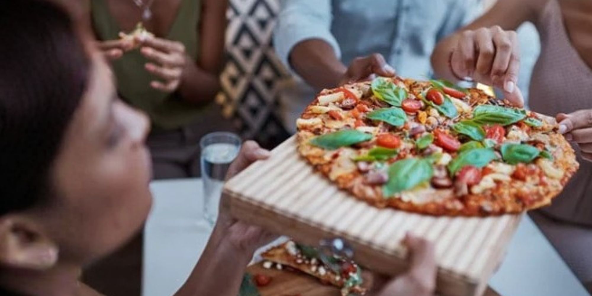 South African friends sharing homemade pizza cooked in an outdoor gas pizza oven